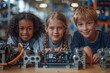 Three young kids collaborating on assembling and studying robots in a technology workshop setting