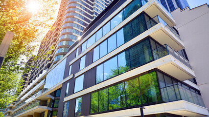 Wall Mural - Eco architecture. Green tree and new residential building. Harmony of nature and modernity. Modern apartment building with new apartments in a green residential area.