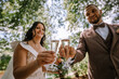 © Raivo - Valmiera, Latvia- July 28, 2024 - A bride and groom are toasting with champagne glasses, smiling on their wedding day in an outdoor setting.