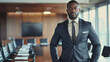A dapper black man commands attention in the boardroom dressed in a finely tailored suit and polished shoes. His strong posture and determined expression demonstrate his unwavering .