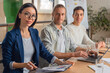 © InsideCreativeHouse - Happy group of businesspeople during business meeting. Colleagues looking at camera and smiling while sitting in boardroom in office