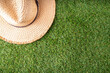 Spring, summer picnic, outdoor recreation background. A woman's straw hat, a picnic blanket or tablecloth, sunscreen spray, an apple on a background of green artificial grass or lawn, copy space