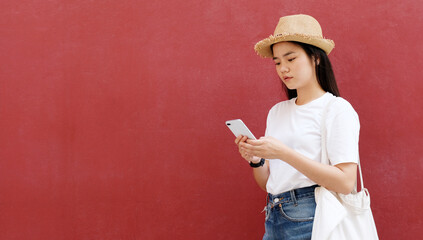 Wall Mural - Young asian woman using phone with smiling, happy and relax emotion, over red background with copy space, Happy asia girl on phone, people and technology, lifestyle