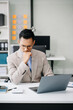 © Nuttapong punna - Frustrated young businessman working on a laptop computer sitting at his working place .