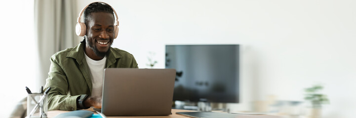 happy african american man in headset working on laptop computer