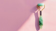 Jade facial roller on pink background with copy space Top view : Generative AI