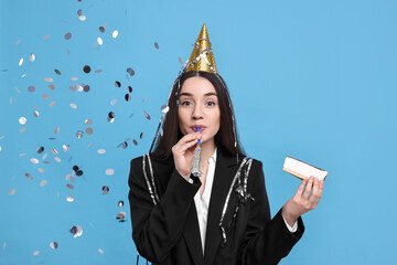 Canvas Print - Woman in party hat with blower, piece of tasty cake and flying confetti on light blue background