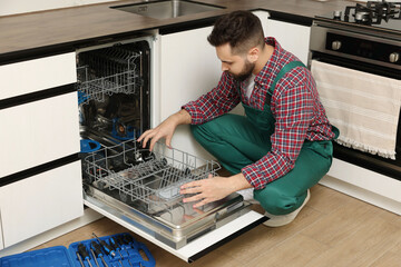 Canvas Print - Serviceman examining dishwasher lower rack in kitchen