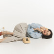 © master1305 - Young beautiful woman with retro makeup, lying on floor and talking on vintage phone with happiness and joy, isolated on white. Concept of retro and vintage, fashion, human emotions, positive mood