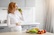 Expectant mother drinking a green smoothie in kitchen