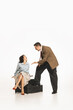 © master1305 - Man in suit gesturing at seated woman on the floor. Couple quarreling, emotionally arguing. Young elegant woman expressing disagreement. Concept of retro and vintage, relationship, human emotions