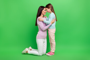 Wall Mural - Full body portrait of two people mother daughter hug touch heads isolated on bright green color background