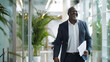 © Generative AI - Laughing African American businessman walking in an office holding paperwork after a meeting with colleagues : Generative AI