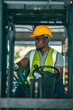 © chokniti - A man in a yellow safety vest and a hard hat is sitting in a forklift cab