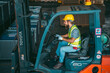 © chokniti - A man in a yellow helmet is driving a forklift
