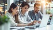 © Rakchanika - Group of Happy Asian business people are looking at their business plans together on their laptop screens, meeting in modern co-working space, businesswomen and partnership sitting against sunlight