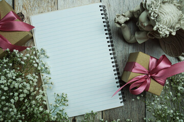 Poster - Notebook and gift boxes with pink ribbon and flower decoration on wooden background