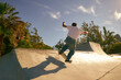 Back view of young man doing tricks on his skateboard at the skate park. Active sport concept