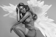 Beautiful sexy blonde woman in elegant lingerie and angel wings is sensually posing in studio. Angel in lingerie, black and white artistic photo