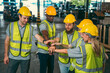 © chokniti - In a factory setting, a team of engineers and foremen emphasize safety and teamwork during a meeting, ensuring success in the construction industry.