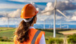 Mulher de costas, vestindo uniforme de construção laranja, capacete de construção, observando campo de energia eólica.