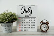 © may1985 - July 2024 monthly calendar with vintage alarm clock on wooden background