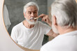 © New Africa - Senior man combing mustache near mirror in bathroom