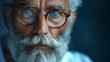Close-up portrait of a senior man with blue eyes wearing round glasses. Intense and wise facial expression suggesting life experience and stories