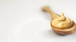 Selective focus on Dijon mustard on top of wooden spoon on white background The wooden spoon is blurry Copy space : Generative AI