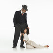 © master1305 - Man in vintage suit with hat stands over woman in cream outfit kneeling. Woman feeling sad about man leaving. Concept of retro and vintage, fashion, romance, relationship