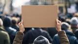 Fototapeta Kosmos - A person holding an empty cardboard sign at the front of a crowd