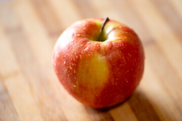 Poster - Red apple lying on the table on the sunshine, close up. Food, fruit, vitamin, nutrition concepts