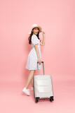 Fototapeta  - Happy young Asian woman traveler drag luggage isolated on pink background, Tourist girl having cheerful holiday trip concept, Full body composition