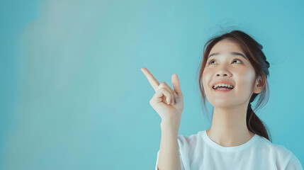 beautiful young asian woman pointing up to copy space and look aside to space with smile face and ha