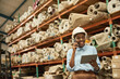 African woman with a tablet and phone standing in a warehouse