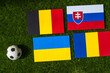 Belgium Leads Group E: Flags of Belgium, Slovakia, Romania, Ukraine, and soccer ball on green grass at Europe football tournament in Germany in 2024