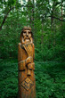 ritual wooden pagan idol in forest, abstract natural green background. old god totem in traditional Slavic folk style. bearded old man with wheat in his hands. Attribute of pagan religious rites.