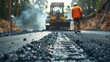 Road construction workers and machinery laying asphalt