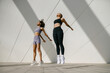 Women athlete in sportswear leaping in air with wall backdrop outdoors. Healthy lifestyle concept