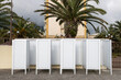 A row of white cubicles with a palm tree in the background