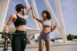 Happy female friends doing gesture of sport shake hand after training outside