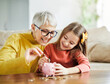 © Lumos sp - child money saving grandfmother family coin senior finance bank piggybank happy investment granddaughter girl financial elderly cash