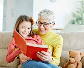 Wall Mural - grandchild family child grandparent grandmother book reading elderly granddaughter girl  happy together read learning education woman