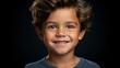 Portrait of a cute little boy on a black background. The boy is smiling.
