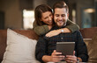 © peopleimages.com - Home, hug and couple with tablet, love and search for restaurant or social media post with romance in lounge. Apartment, embrace or woman with man on couch and tech with online reading or digital app