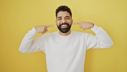 Canvas Print - Cheerful young man showing his perfect white teeth, pointing at mouth with finger - celebrating dental health on a sunny yellow background