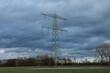 electricity pylon in a meadow under a dark, clouded sky