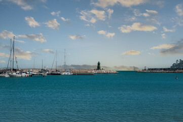 Wall Mural - Pier with yachts on the seashore with a lighthouse in Italy