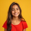 A bright-eyed Hispanic teenager with a radiant smile and curly hair, dressed in a yellow top against a sunny yellow backdrop, exudes joy and youthful energy.