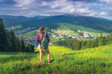 Wall Mural - girl on the hill with yellow flowers and green grass in beautiful alpine mountain valley at sunset i